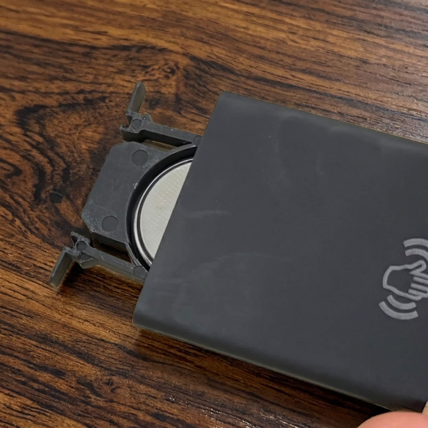 Close-up view of the slim black remote control featuring a slide-out battery tray and wall mount dock for easy wall panel brightness adjustments.