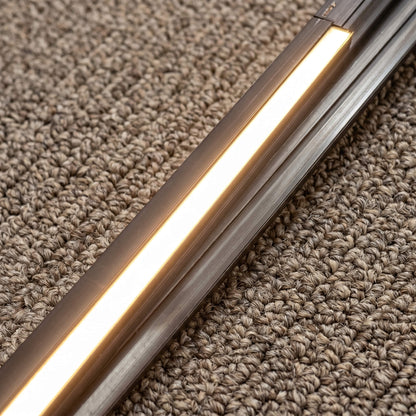 Close-up detail of a 13mm wide slim black LED track channel lit with warm ambient light, showing its seamless, flush profile integrated without a visible edge trim.