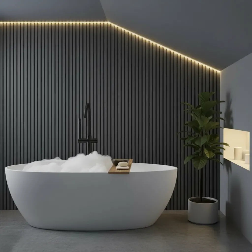 Modern bathroom interior featuring luxury dark grey PVC slat wall panels as an accent wall behind a white freestanding bathtub with ambient LED lighting.