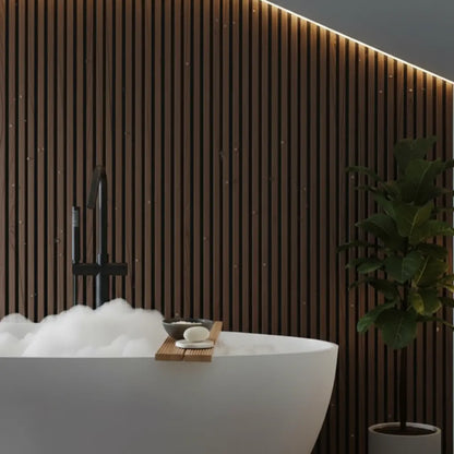 Luxury spa bathroom design featuring dark oak wood effect PVC slat wall panels behind a white freestanding bubble bath with warm accent lighting.