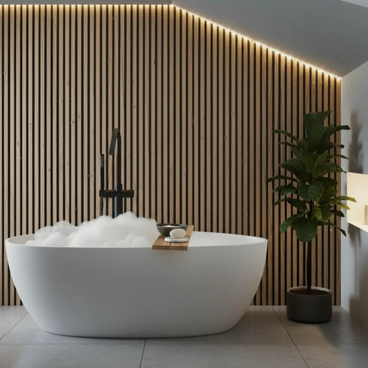 Modern bathroom design featuring natural oak color PVC slat wall panels behind a white freestanding bathtub, creating a warm, water-resistant timber look.