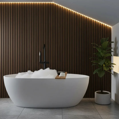 Sophisticated bathroom interior showcasing rich walnut brown PVC slat wall panels as a moisture-proof accent wall behind a white freestanding tub.